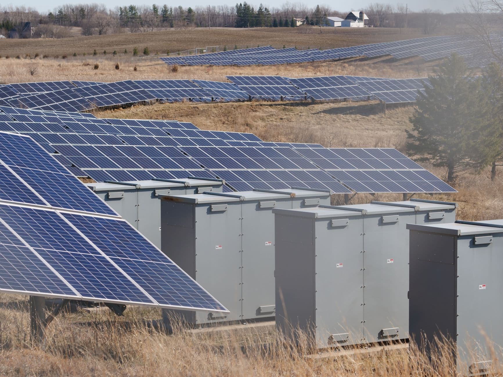 Gran parque solar en una llanura polaca con contenedores de baterías y estaciones de inversores junto a los paneles.